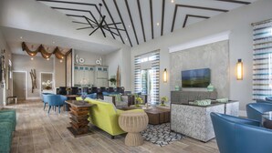A spacious living area with a modern kitchen, a dining area, and a seating area with blue chairs and a green sofa. - Veranda Palms 2505 (Kissimmee)