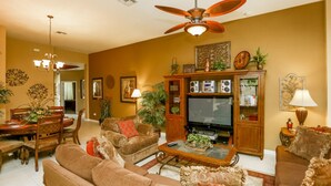 A living room with a sofa set, a coffee table, a television, and a ceiling fan. - Windsor Hills 7718 (Kissimmee)
