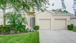 A single-story house with a garage, a front yard with a palm tree, and a well-maintained lawn. - Windsor Hills 7718 (Kissimmee)