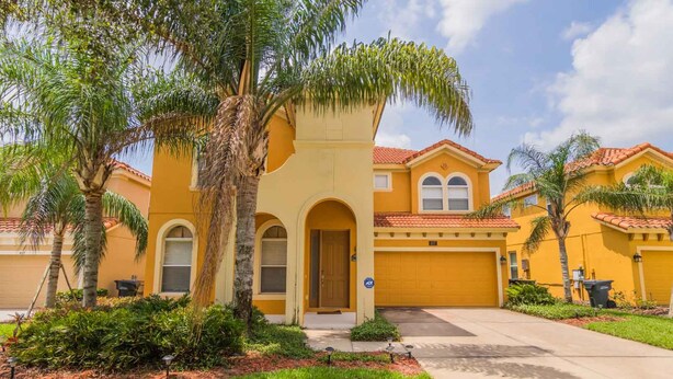 A yellow two-story house with a red-tiled roof, a front entrance, and a garage. - Watersong 457 (Davenport)