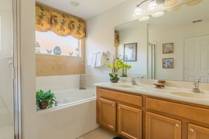 A bathroom with a bathtub, wooden vanity, and a large mirror.
