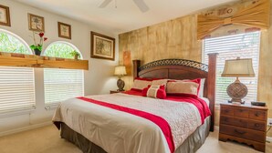 A bedroom with a large bed, a nightstand, a dresser, and a window with blinds. - Watersong 457 (Davenport)