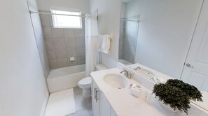 A modern bathroom with a bathtub, toilet, and sink. - Encore Resort at Reunion 7711 (Kissimmee)