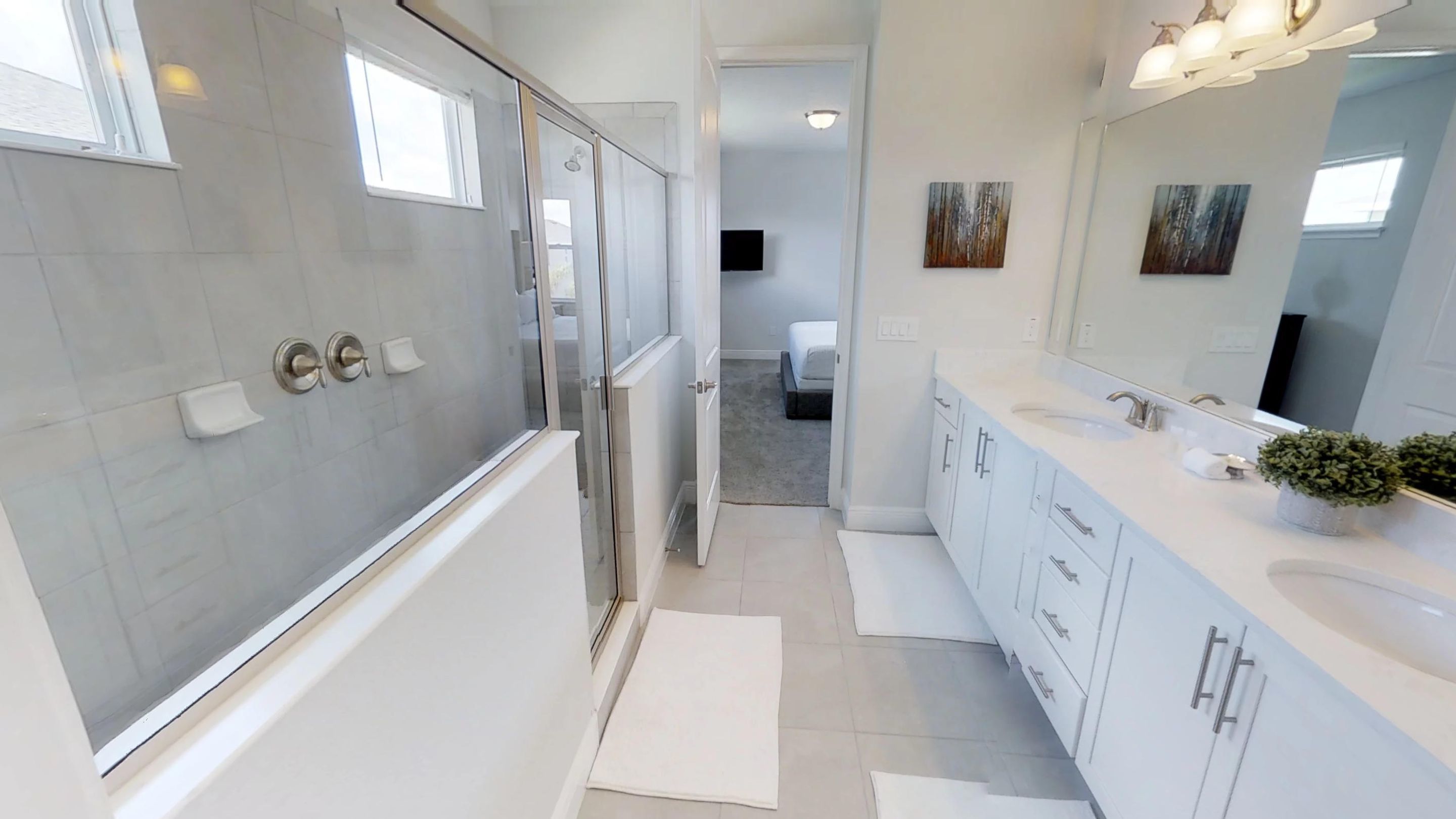 A modern bathroom with a glass shower enclosure, white cabinetry, and a large mirror.