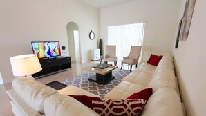 A living room with a sofa, chairs, a coffee table, a TV, and a lamp. - Crystal Cove 1014 (Kissimmee)