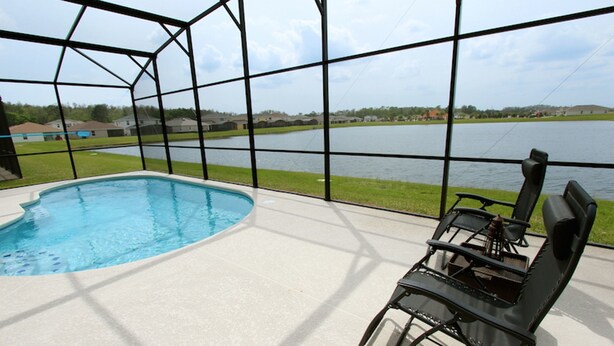 An indoor swimming pool with a view of a lake and houses in the background. - Crystal Cove 1014 (Kissimmee)