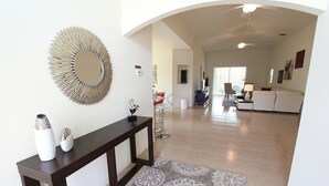A spacious living area with a dark wooden console table, decorative vases, and a large mirror. - Crystal Cove 1014 (Kissimmee)
