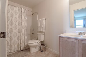 A bathroom with a toilet, shower curtain, and sink. - Compass Bay 3133 (Kissimmee)