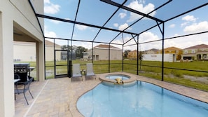 Ein überdachter Pool im Freien mit Whirlpool, Terrassenmöbeln und Grillplatz.
