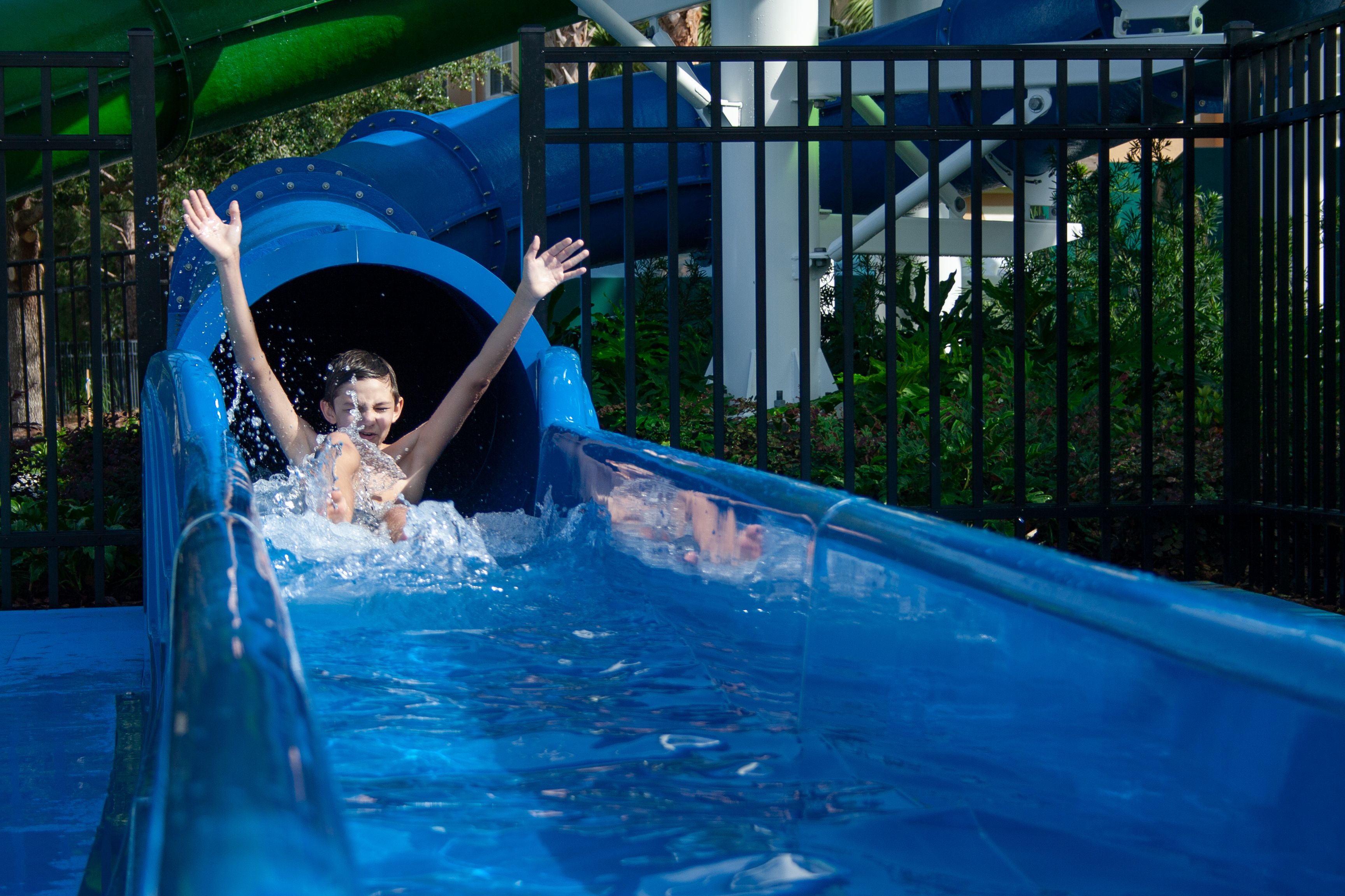 A water slide at a theme park with a blue slide and a water splash area.