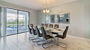 A dining area with a large table, modern chairs, and a chandelier. - Storey Lake 2927 (Kissimmee)