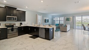 A modern kitchen with dark cabinets, stainless steel appliances, and a marble floor. - Storey Lake 2927 (Kissimmee)