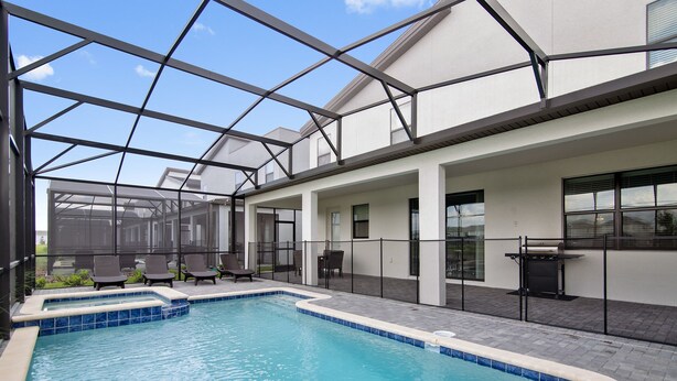 A swimming pool with a glass enclosure, lounge chairs, and a barbecue area. - Storey Lake 2927 (Kissimmee)