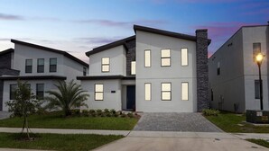A modern two-story residential building with a flat roof, large windows, and a stone accent wall. - Storey Lake 2927 (Kissimmee)