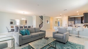 A modern living room with a grey sofa, a glass coffee table, and a patterned rug. - Storey Lake 2927 (Kissimmee)