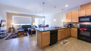 A modern kitchen with wooden cabinets, a black dishwasher, and a microwave. - Compass Bay 3181 (Kissimmee)