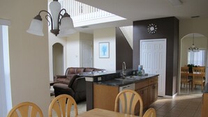 Une cuisine spacieuse avec un coin repas, un salon doté d’un canapé et un escalier menant à l’étage supérieur.