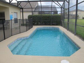 A rectangular indoor swimming pool with a beige tiled floor and a black mesh fence surrounding it. - Cumbrian Lakes 4645 (Kissimmee)