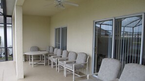 Un patio couvert avec un ventilateur de plafond, une table et plusieurs chaises.