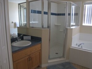 A bathroom with a glass-enclosed shower, a sink, and a bathtub. - Cumbrian Lakes 4645 (Kissimmee)