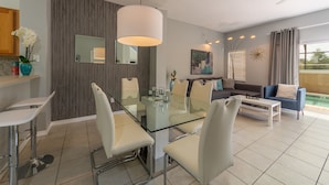A modern living room with a glass dining table, white chairs, a sofa, and a coffee table. - Encantada Resort 3143 (Kissimmee)