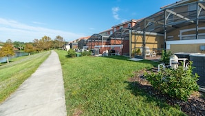 A row of residential buildings with attached garages, a paved walkway, and outdoor air conditioning units. - Encantada Resort 3143 (Kissimmee)