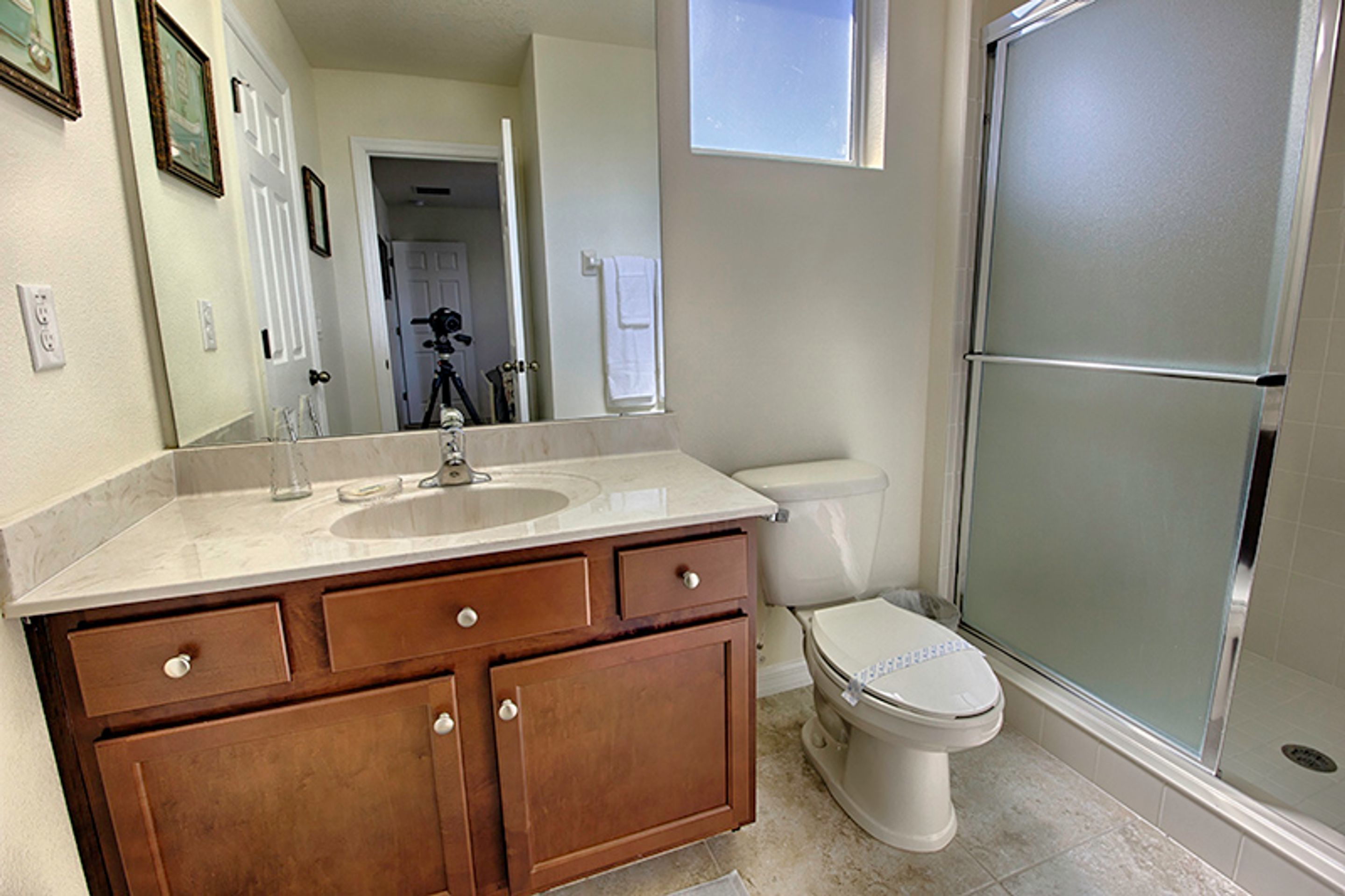 A bathroom with a sink, mirror, toilet, and shower.