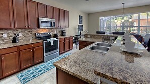 A modern kitchen with granite countertops, stainless steel appliances, and wooden cabinets. - Bella Vida 210 (Kissimmee)