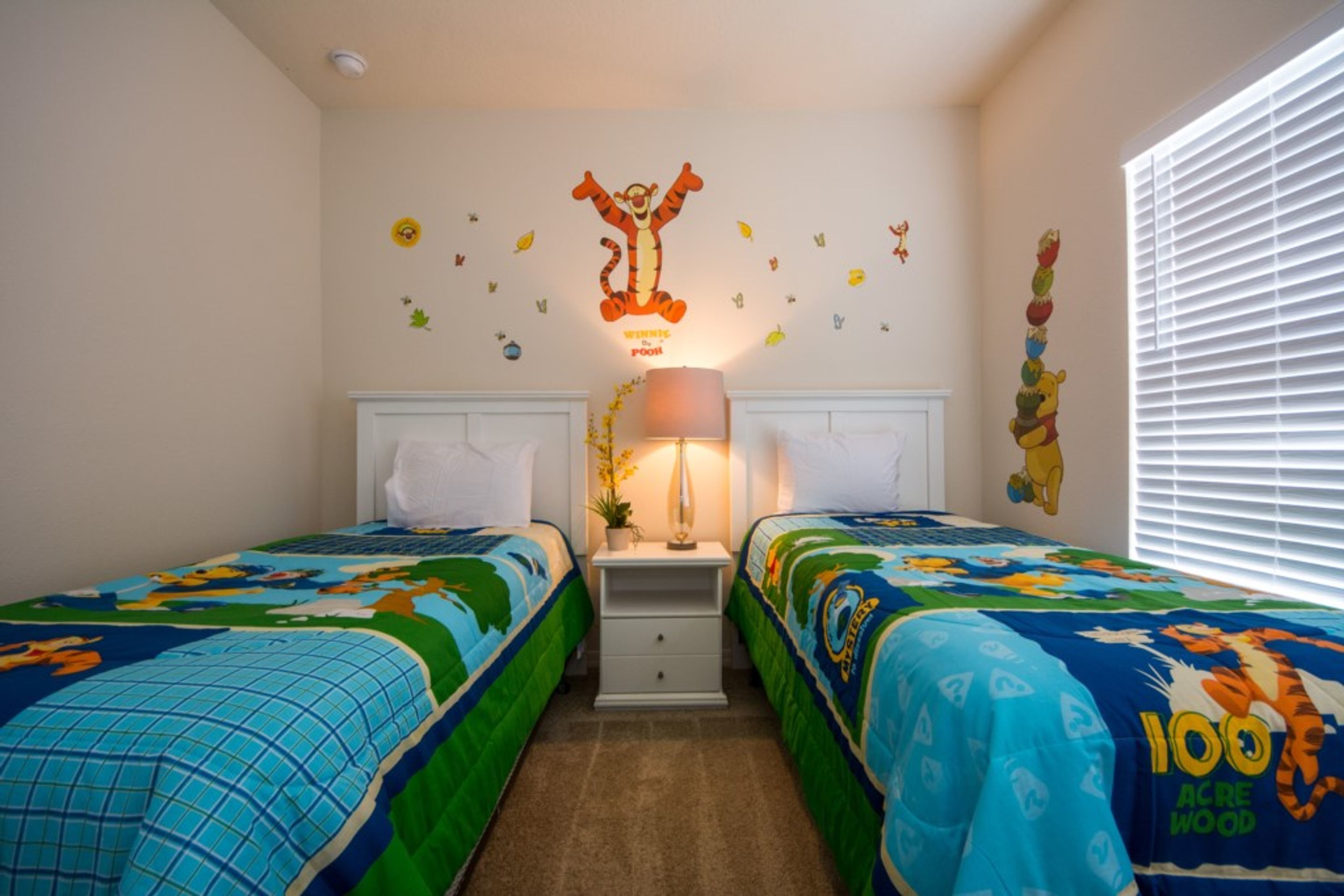 A bedroom with two beds, a nightstand, a lamp, and a wall decoration.