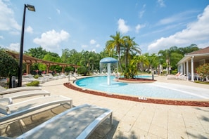 Un espace piscine avec des chaises longues, un palmier et un kiosque.