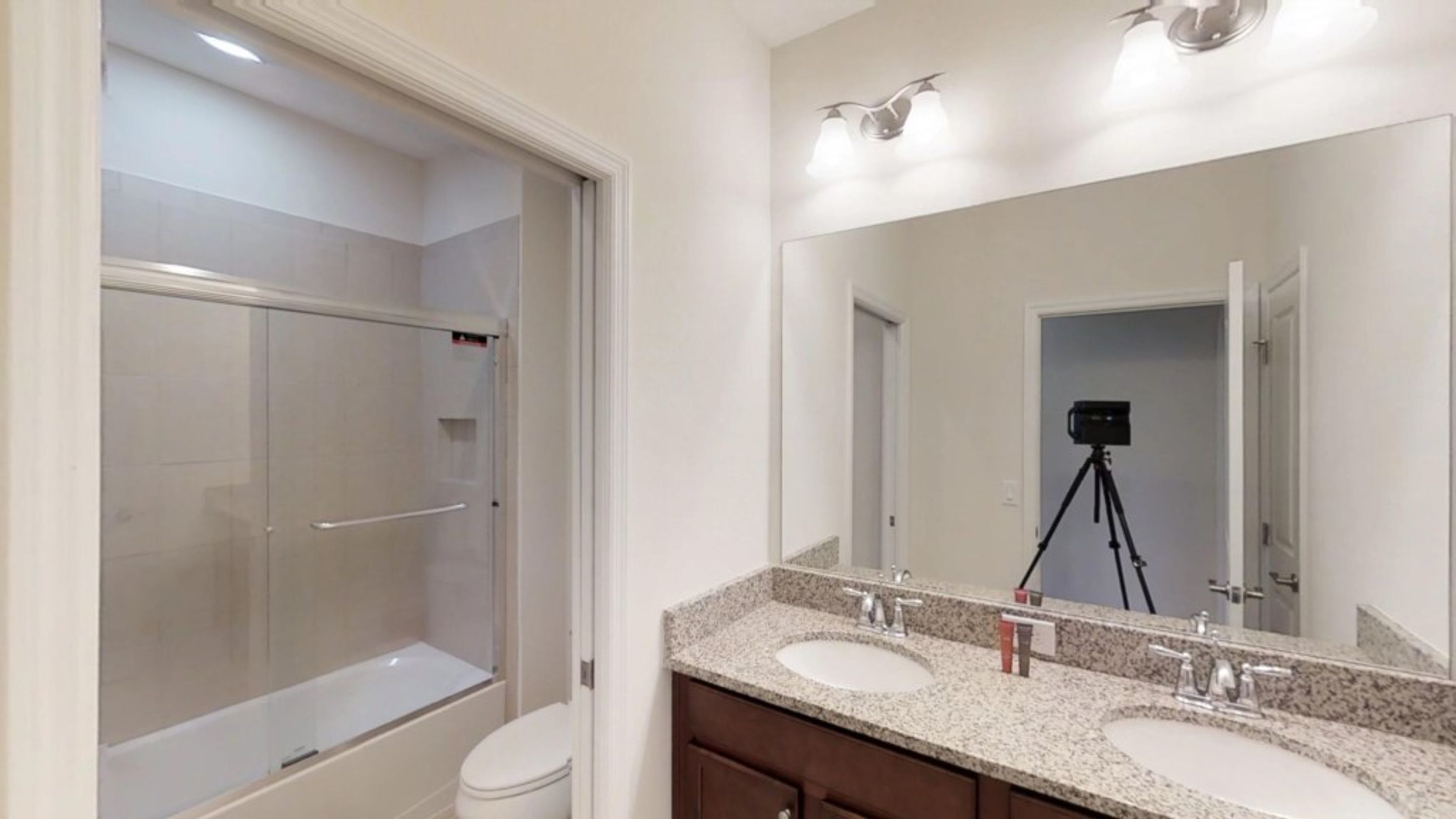 Une salle de bain moderne avec une douche à l’italienne, des toilettes et un meuble-lavabo doté de deux vasques.