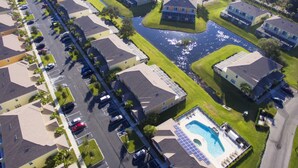 An aerial view of a residential area with houses, a swimming pool, and a body of water. - Serenity 17428 (Clermont)