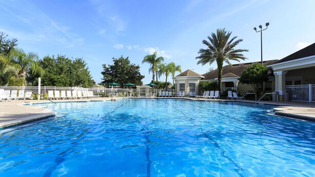 A clear blue swimming pool with lounge chairs and palm trees in the background. - Windsor Palms Condos 8102 - 305 (Kissimmee)