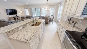 A modern kitchen with granite countertops, stainless steel appliances, and a dining area with a view of the outdoors. - Golden Palms Vacation Resort 4429 (Kissimmee)