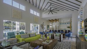 A spacious living area with a high ceiling, large windows, and a modern kitchen in the background. - Golden Palms Vacation Resort 4429 (Kissimmee)