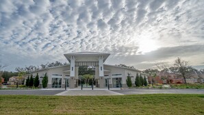 A modern building with a central atrium and a large glass entrance, surrounded by a well-maintained lawn and residential houses. - Veranda Palms 2652 (Kissimmee)