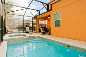 Ein Swimmingpool mit Glasveranda, Liegestühlen und Grillplatz.