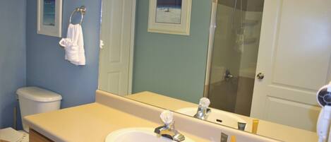 Une salle de bain avec un lavabo, un miroir et des toilettes.
