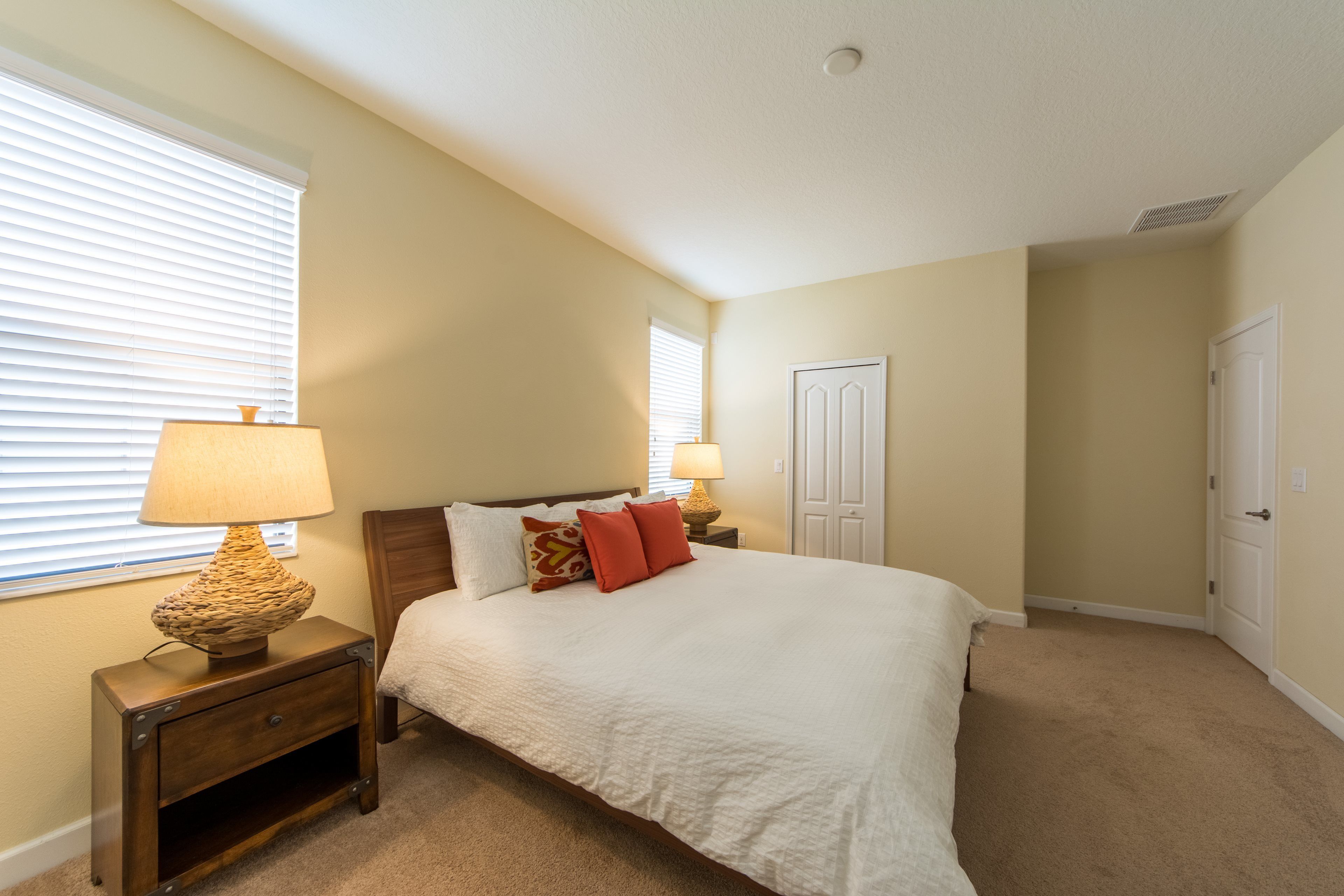 A bedroom with a bed, two bedside tables, a lamp, and a door.