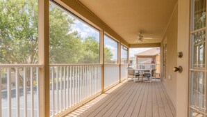 A covered porch with a table and chairs, large windows, and a ceiling fan.