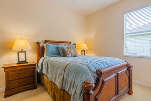 Een slaapkamer met een houten bed, twee nachtkastjes en een raam met zonwering.