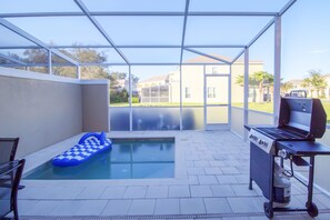 A covered outdoor area with a swimming pool, a barbecue grill, and a blue inflatable lounge.