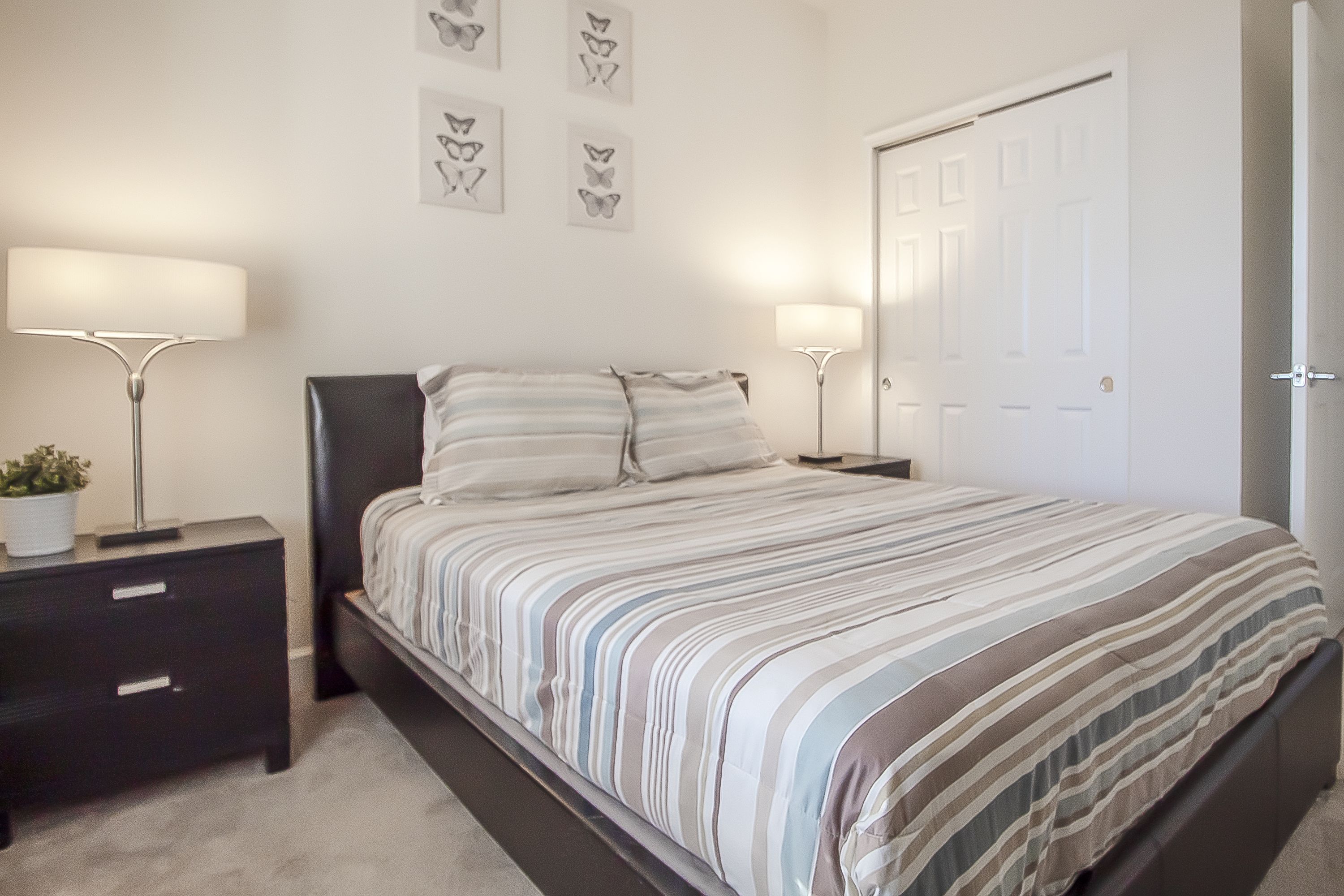 A bedroom with a bed, two bedside tables, a nightstand, and a door.