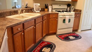 A kitchen with wooden cabinets, a white stove, a microwave, and a coffee maker. There are two coffee mugs on the counter. - Orange Tree 3434 (Clermont)