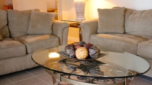 A living room with a glass coffee table, beige sofas, and a lamp. - Orange Tree 3434 (Clermont)