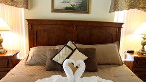 A bed with a wooden headboard, two pillows, and a decorative pillow with a heart design. - Orange Tree 3434 (Clermont)