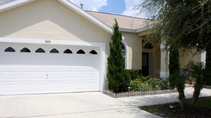 A residential house with a white garage, number 3434, and a well-maintained front yard with a small fence and a palm tree. - Orange Tree 3434 (Clermont)