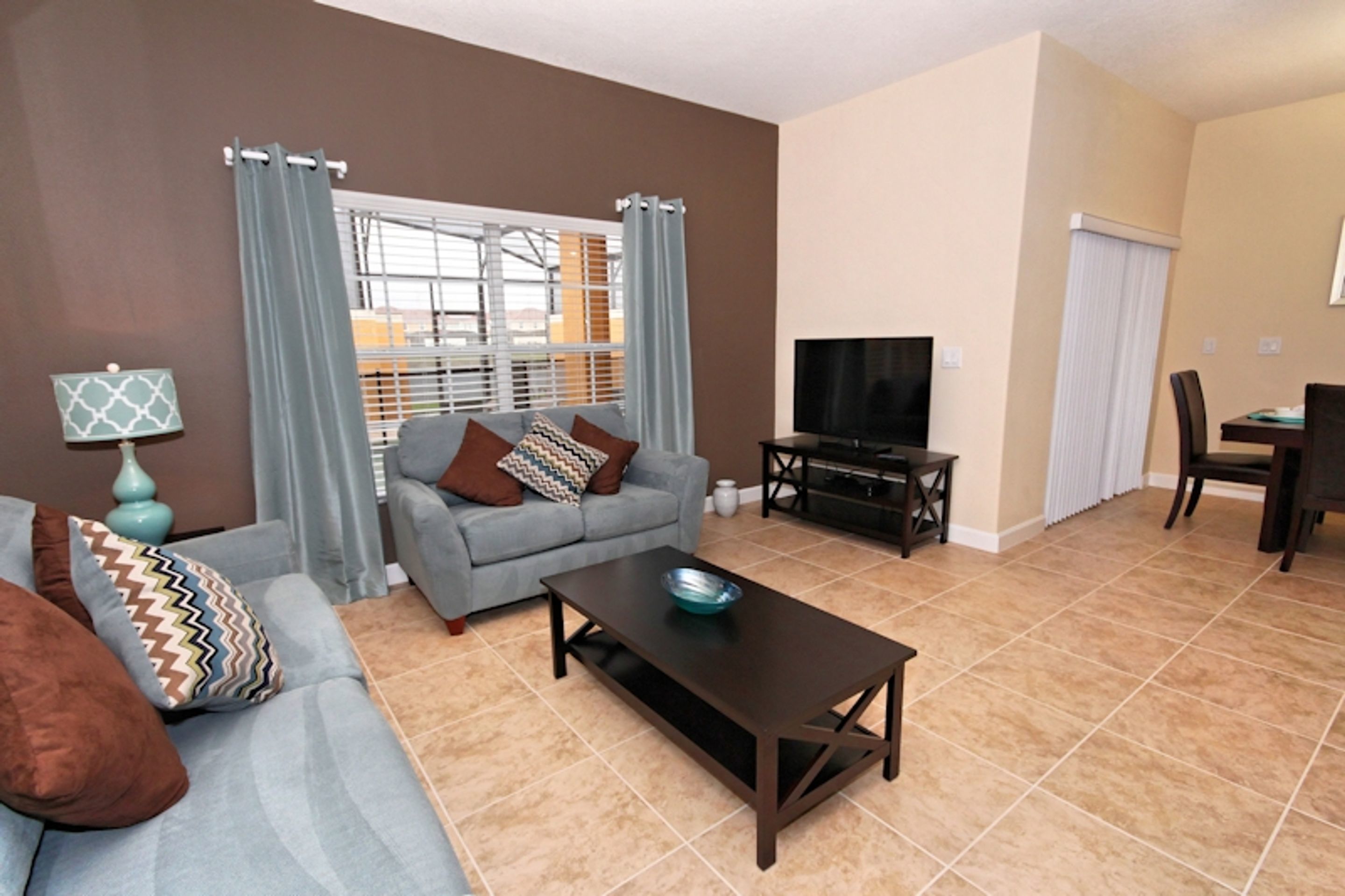 A living room with a sofa, a coffee table, a TV, and a dining area with a table and chairs.