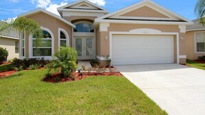A modern two-story house with a garage, large windows, and a well-maintained lawn. - Crystal Cove 929 (Kissimmee)