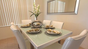 A dining table with six chairs, a vase with flowers, and plates with food. - Crystal Cove 929 (Kissimmee)